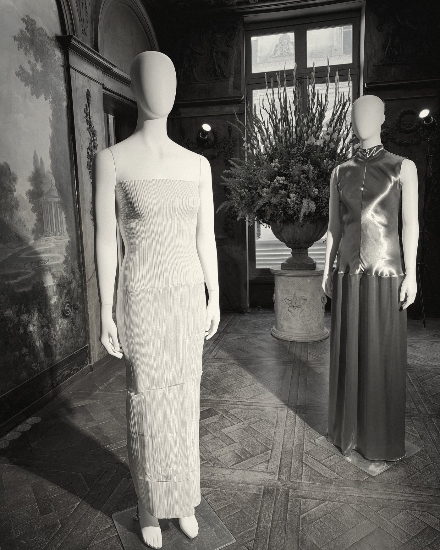 Two gowns on mannequins in a painted Parisian salon
